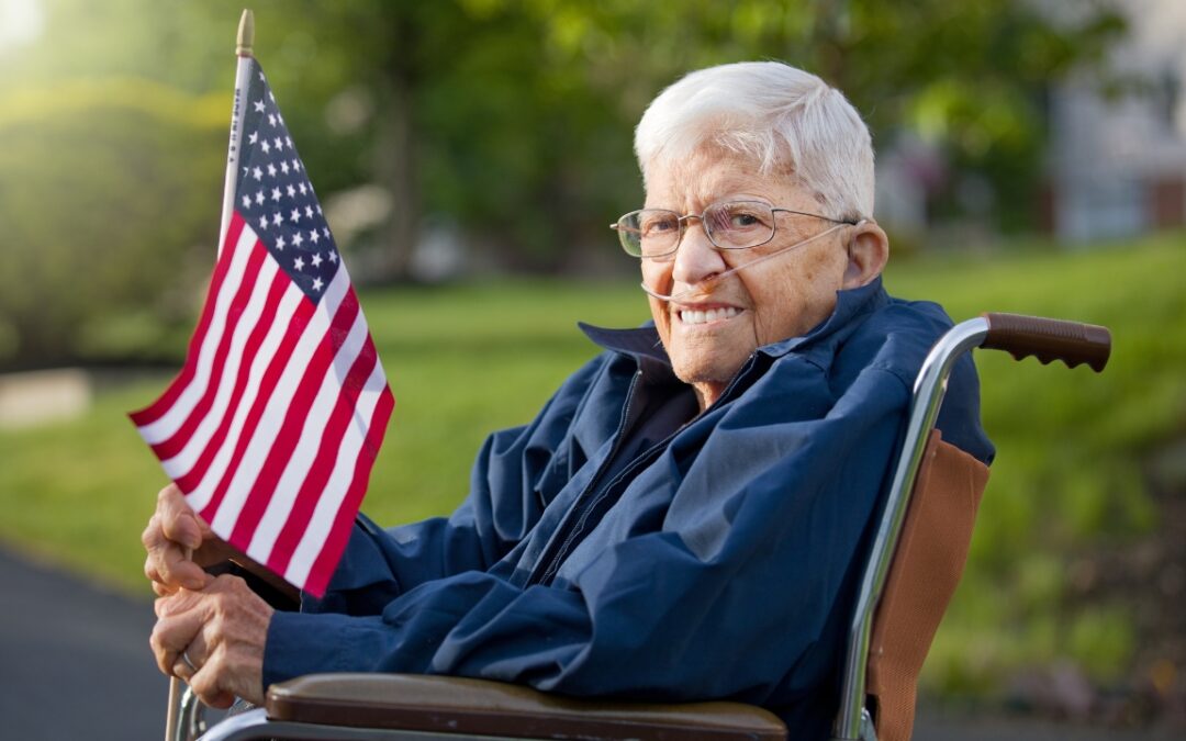 an elderly man sitting in a wheelchair holding an American flag
