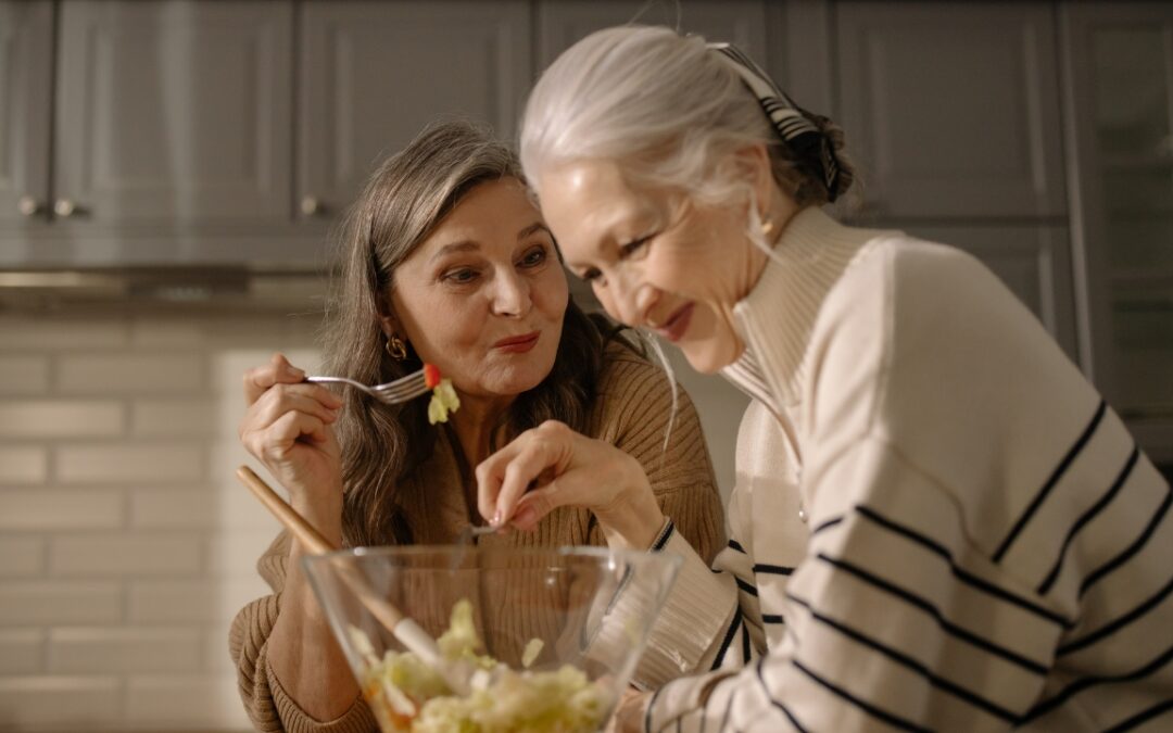 two elderly women eating a salad straight from a salad bowl