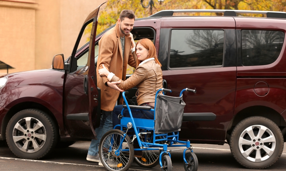 a man helping a woman out of a car and into a wheelchair