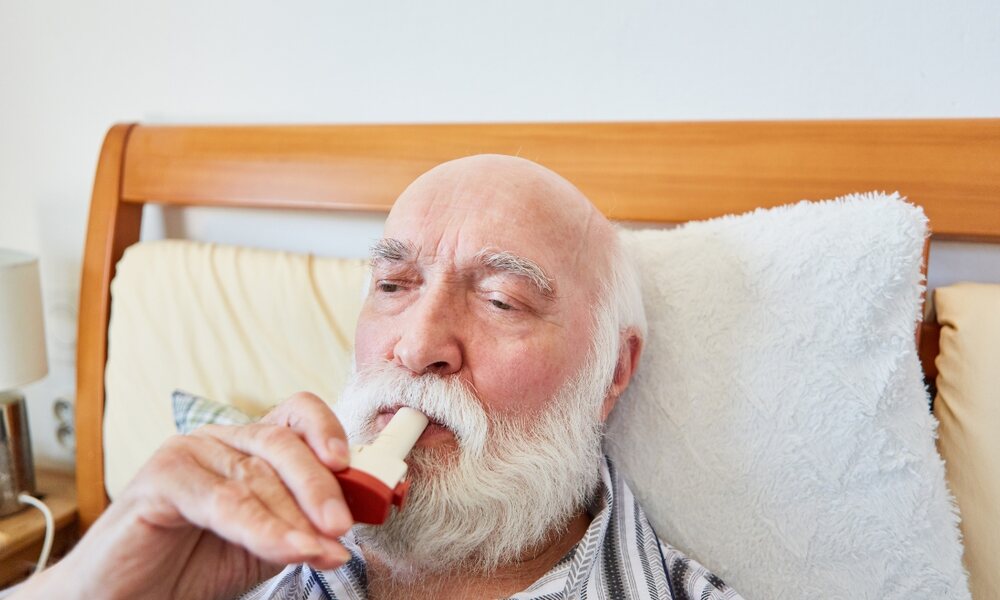 an elderly man using an inhaler