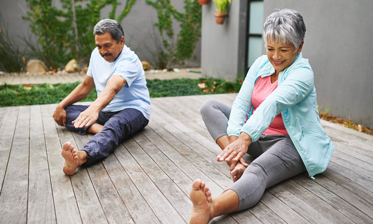 an elderly couple stretching and doing yoga on their porch