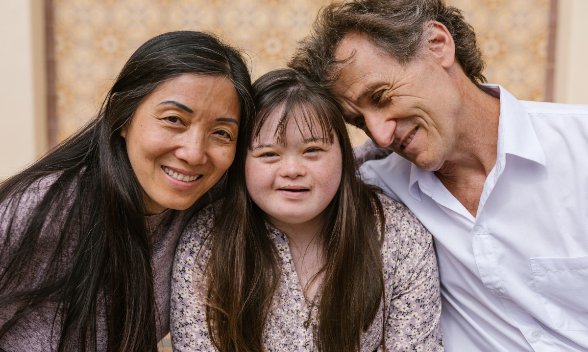 a man and a woman holding their daughter, who has Down syndrome