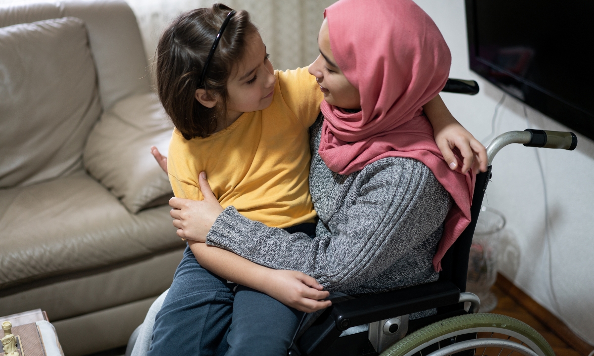 a woman in a wheelchair holding her daughter on her lap