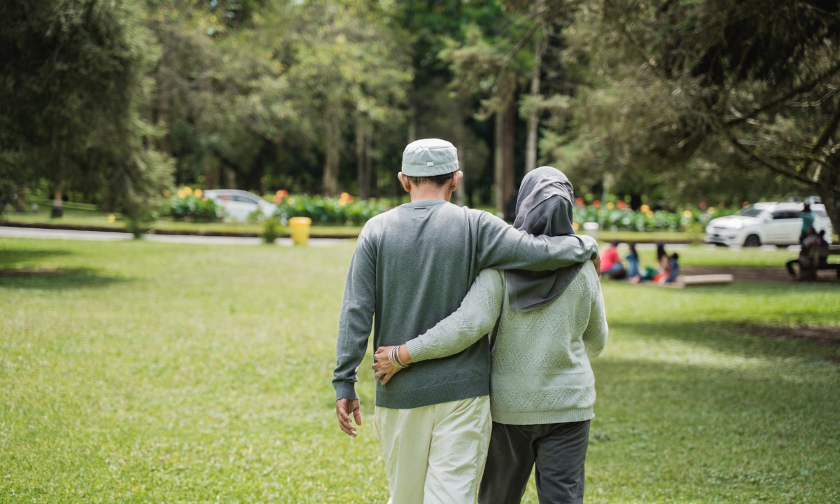 an elderly couple in a park walking away from the camera
