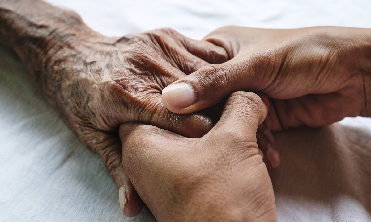 a pair of younger hands holding an older hand