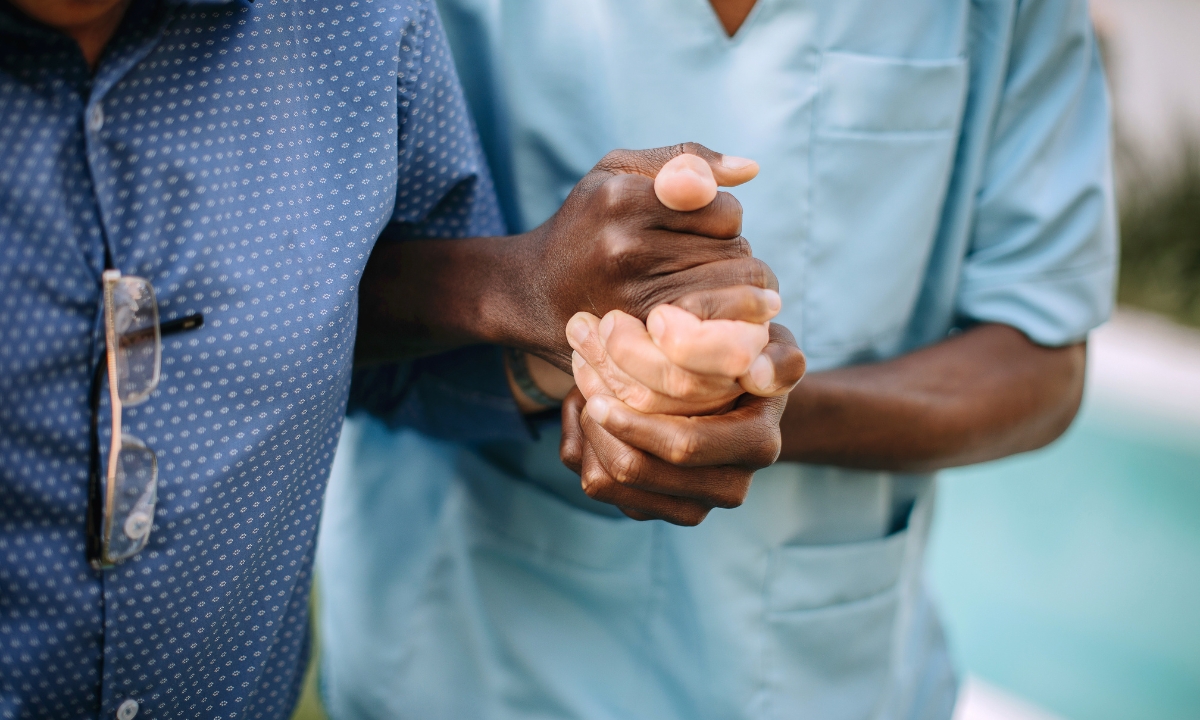 a nurse helping a person walk around. the image is zoomed in on their hands, which are clasped tightly together
