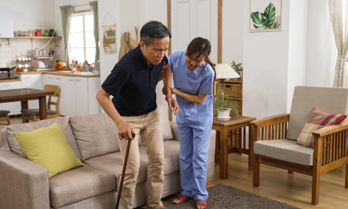 a nurse helping their patient off the couch