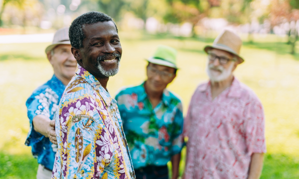 a group of senior men standing in a park and smiling at the camera