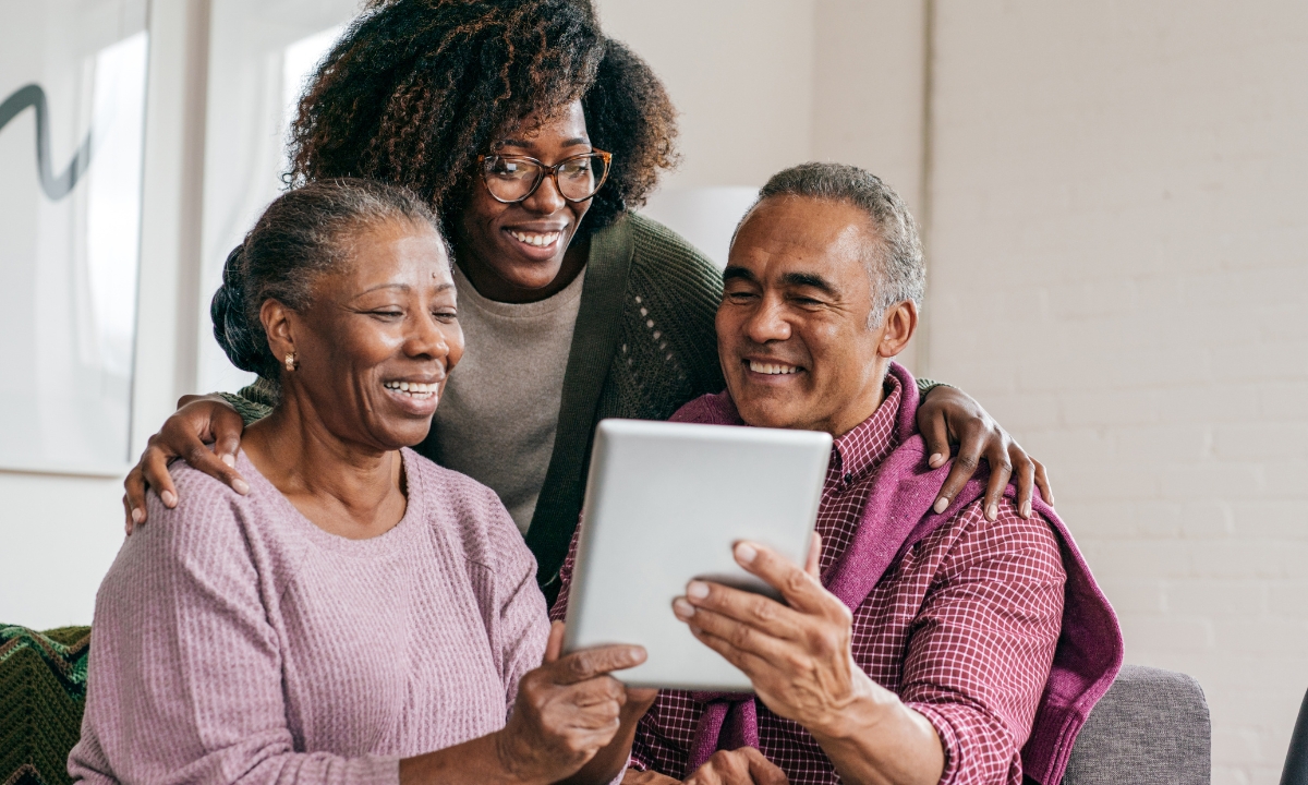 two senior parents and their child looking at a tablet screen