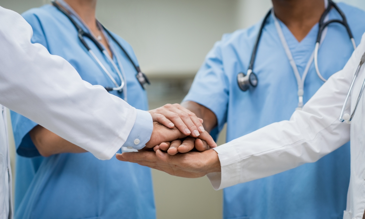 a group of doctors and nurses with their hands in a pile