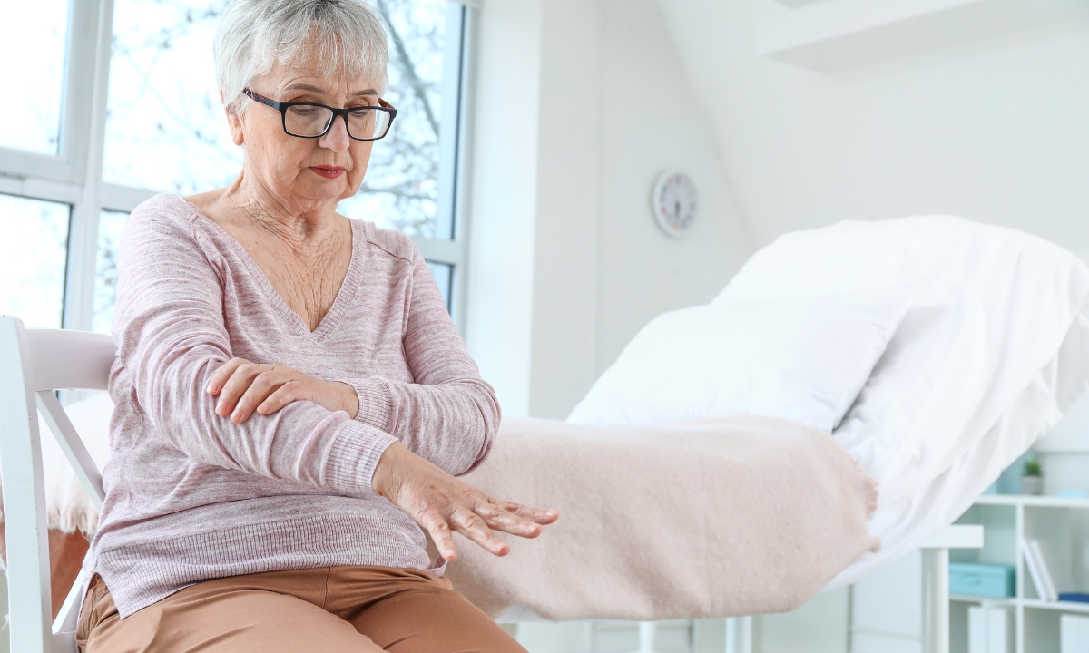 a woman sitting on the edge of a hospital bed holding her arm out