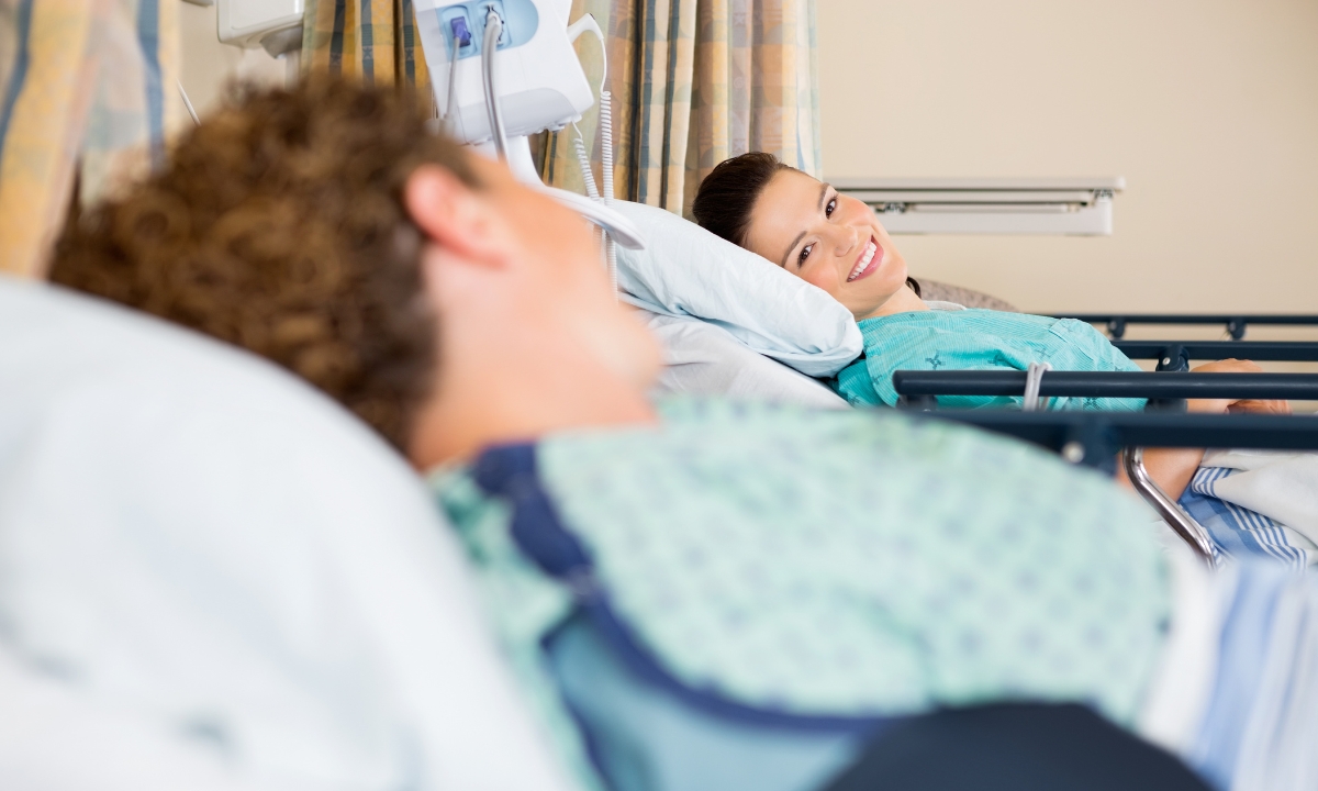 two patients in hospital beds smiling at each other