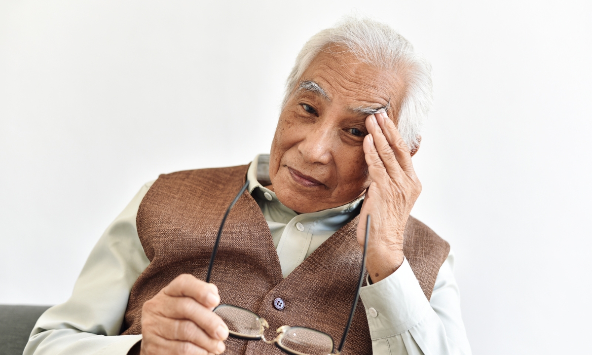 a man holding his glasses and rubbing his brow bone