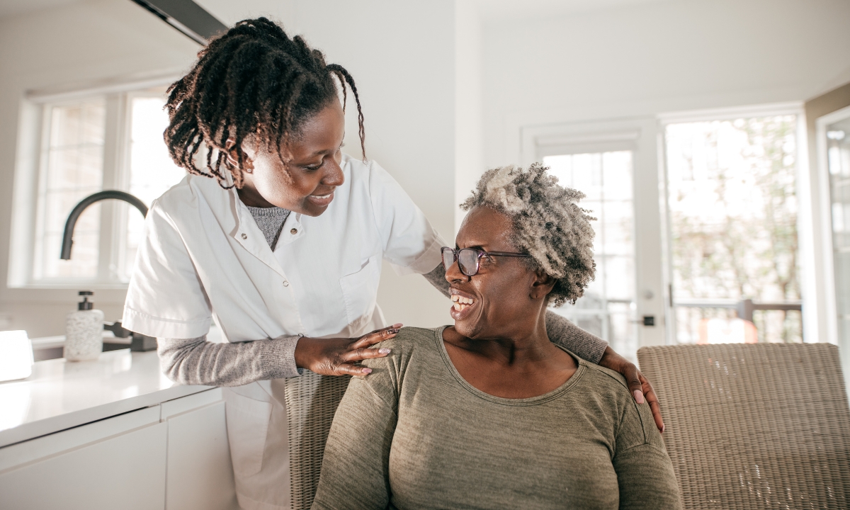 an in-home nurse and their patient smiling at each other