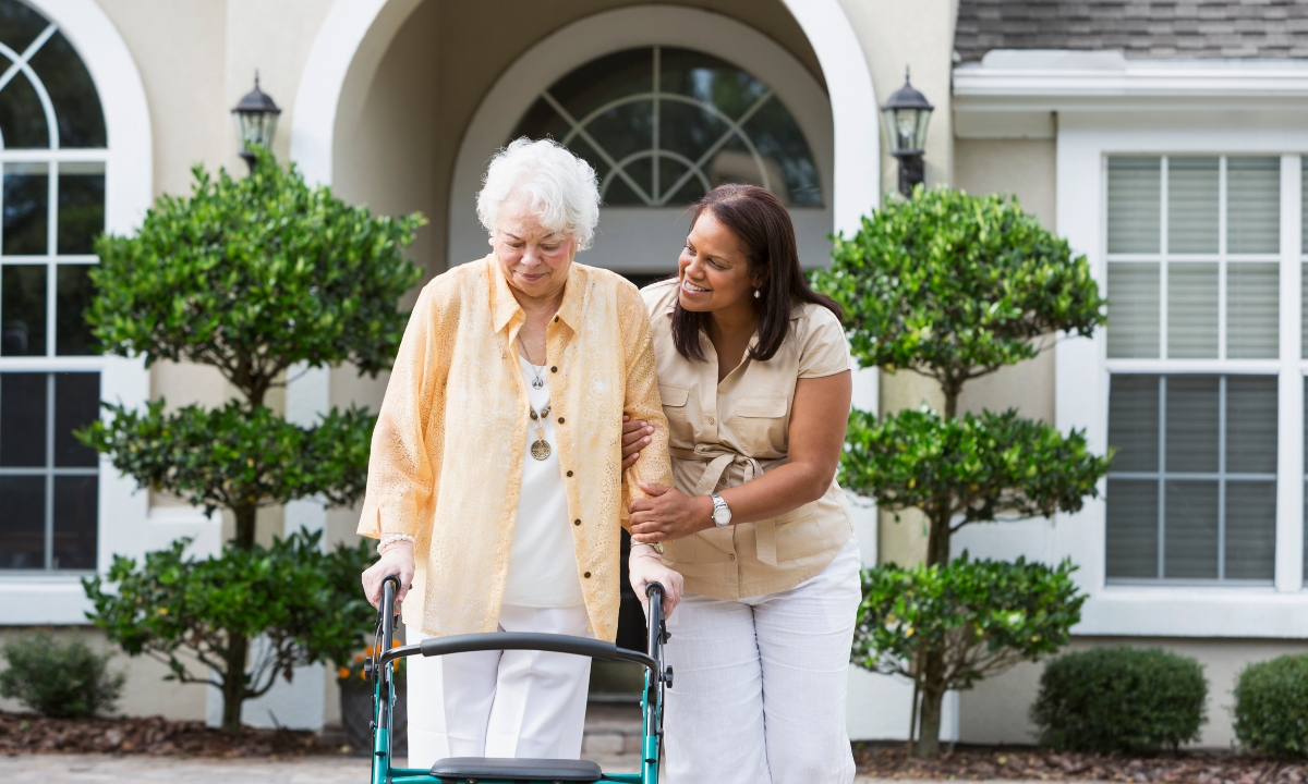 a woman helping her mother to use a walker