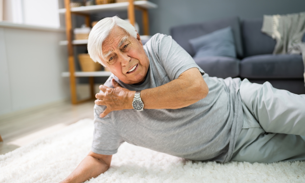 an elderly man on his floor, holding his shoulder after he fell