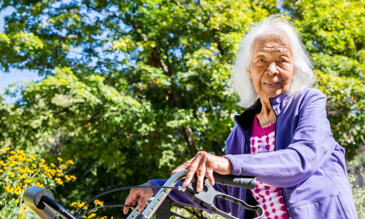 a senior lady using a walker and smiling at the camera