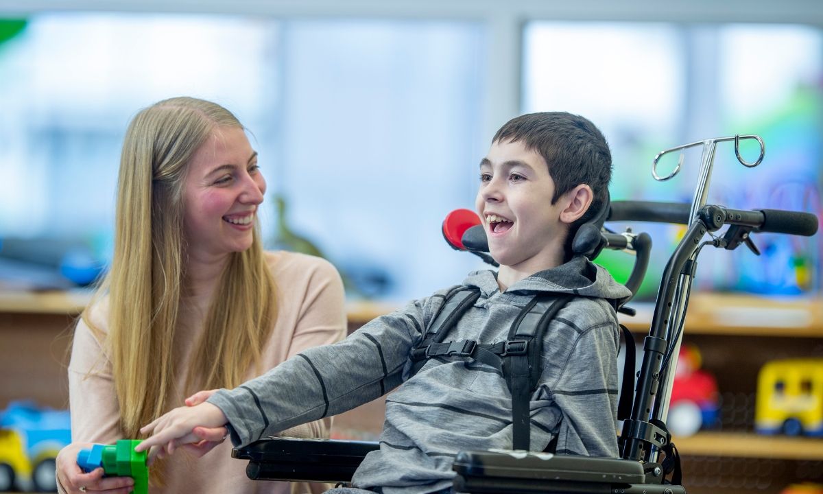 a woman beside a boy with MS in a wheelchair beside her