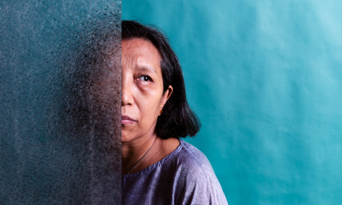 an elderly woman with half her face hidden behind frosted glass