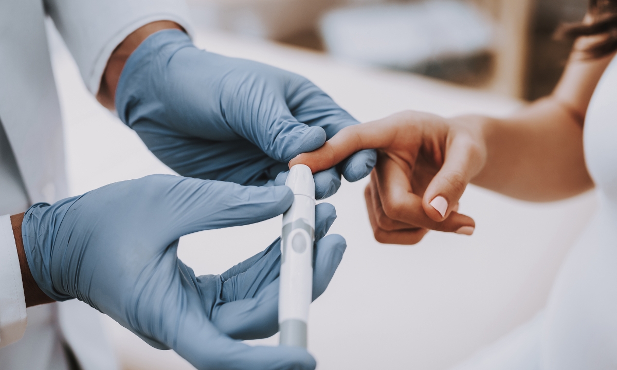 a close-up of a doctor taking someone's blood sugar with a finger prick tester