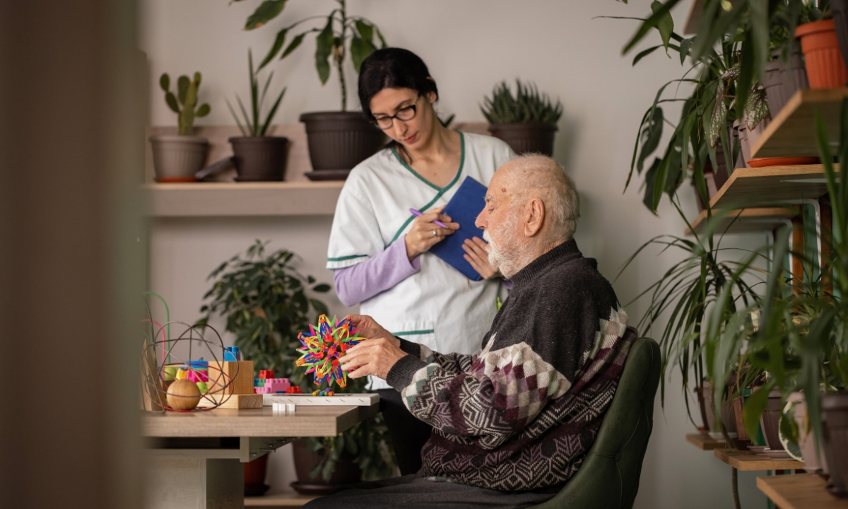 a doctor working with a man with dementia, who is playing with memory-helper toys